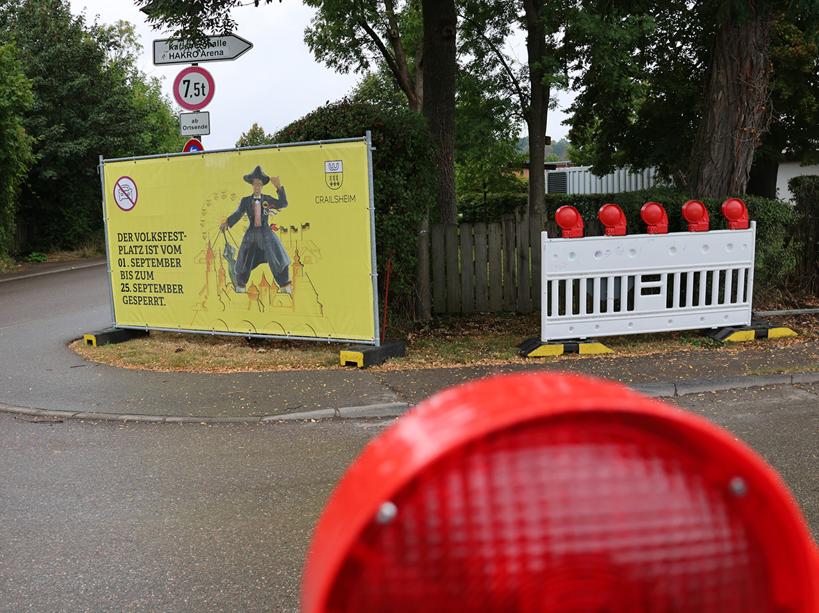 Stadtverwaltung im Vordergrund ein Warnlicht, dahinter eine Straße und ein großes gelbels Banner